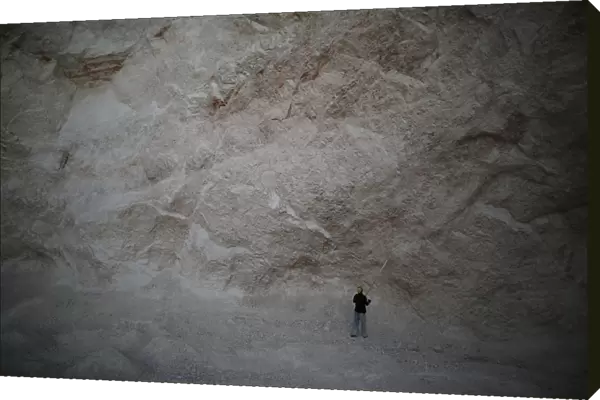 A man uses a long stick to hit rocks and get sand in a sand mine on the outskirts of Fond