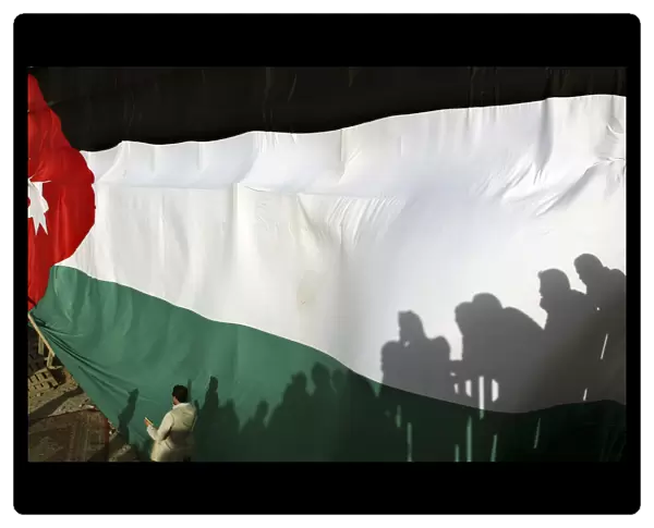 Shadows of people were cast on a large Jordanian national flag during a celebration to