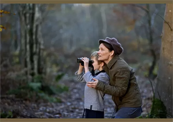 Mother showing son birds in woodland in autumn Norfolk