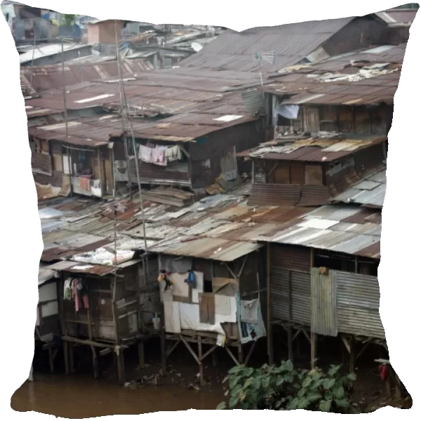 Stilted shacks with corrugated iron roofs beside river in city, Manggarai District, Jakarta, Java, Indonesia, December