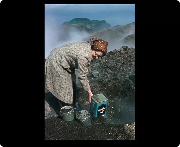 Woman baking bread in heat of lava flow, Eldfell Volcano, Heimaey, Westmann Isles, Iceland, june 1976