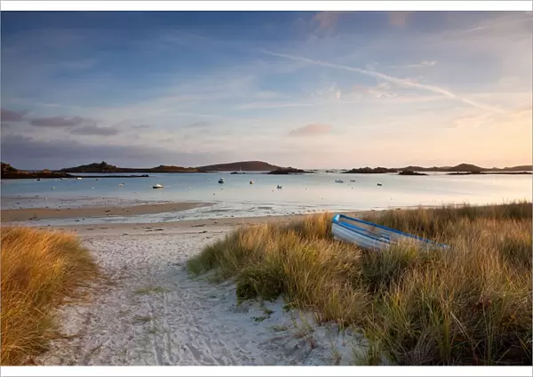 View of boat on beach and moored in bay at sunrise, Porth Green, Old Grimsby, Tresco, Isles of Scilly, England