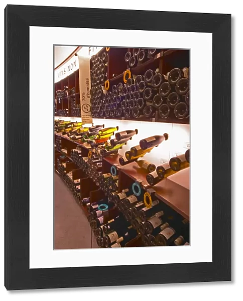 A curved display of bottles. Backlit The Lavinia wine shop in Paris. Probably the