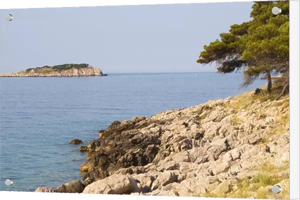 View over coast cliffs with pine trees over the sea water towards an island. Prizba village