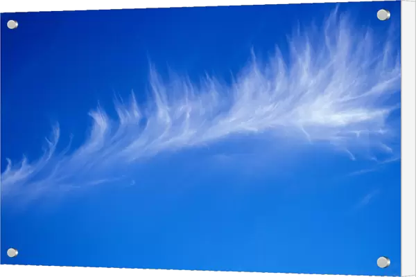 A light whispy cloud hang in the bright blue sky