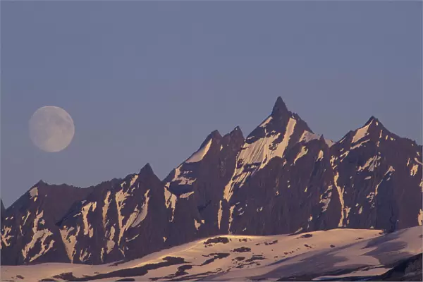 USA, Alaska, Valdez Moon rises above rugged Chugach Range mountains near Valdez