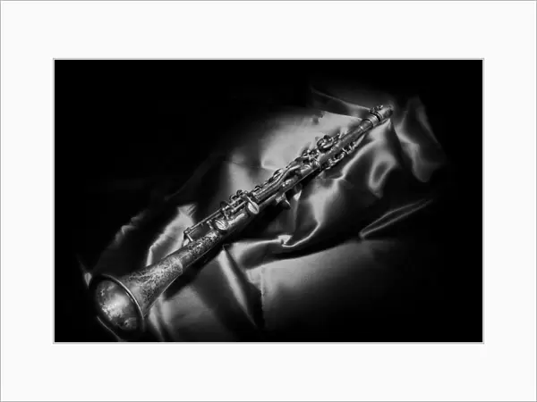 A black and white still life image of a brass clarinet