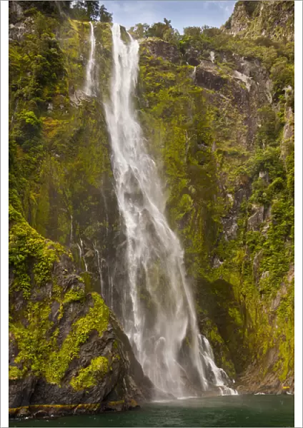 New Zealand, South Island, Fiordland National Park. Waterfall cascades into Milford Sound