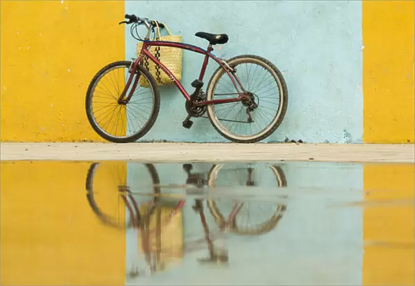 Cuba, Trinidad. Bicycle and reflection against yellow and blue walls