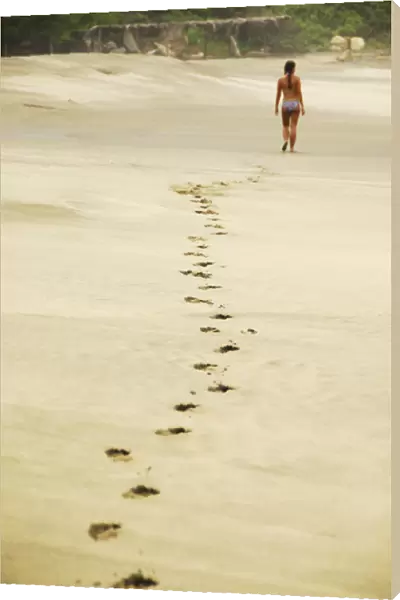 Mexico, Mazunte, view of footprints of woman in bikini walking on sand at the beach