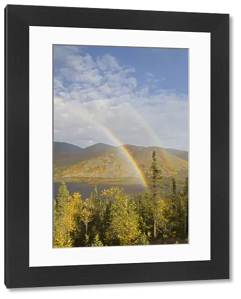A rainbow arcs over autumn colors and Grayling Lake along the James Dalton Highway