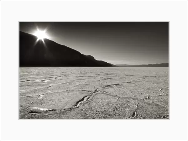 USA, California, Death Valley. Sunburst over salt pan of Badwater Basin. Credit as