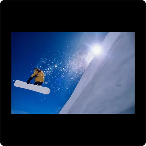 Man flying through the air on a snowboard with the sun over his shoulder in the Wasatch