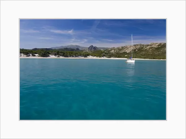 France, Corsica. Sailboat anchored in clear water off white sand of Saleccio Beach