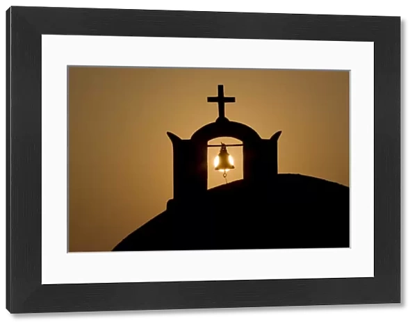 Greece, Santorini, Thira, Oia. Greek Orthodox church cross and bell tower in silhouette