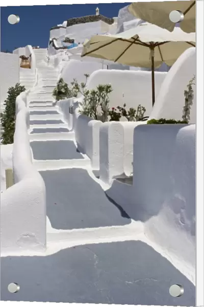 Greece, Santorini, Thira, Oia. Grey and white painted stairs leading past open patio umbrellas
