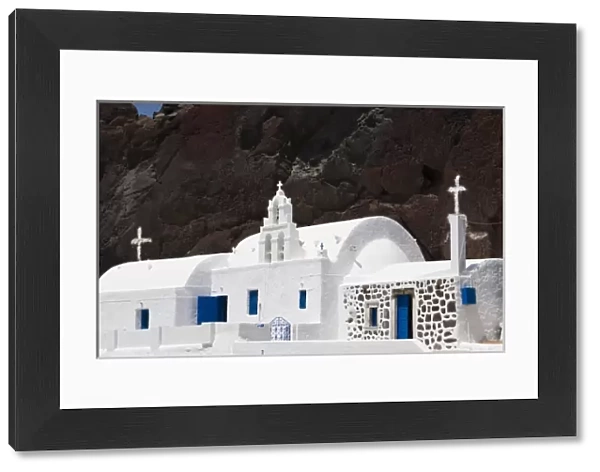 Greece, Santorini. White Greek Orthodox church starkly contrasts with red cliff