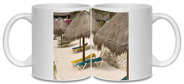 Mexico, Costa Maya. Beach palapas and lounge chairs in village