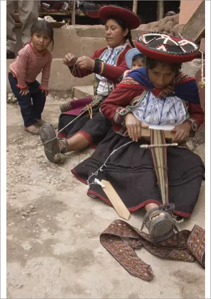 Women in traditional dress and hat weaving using a backstrap loom to weave, Chinchero