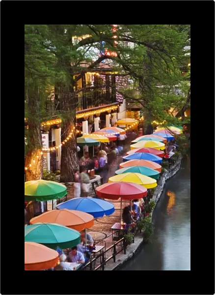 Colorful umbrellas of outdoor cafe along famous River Walk, and San Antonio River
