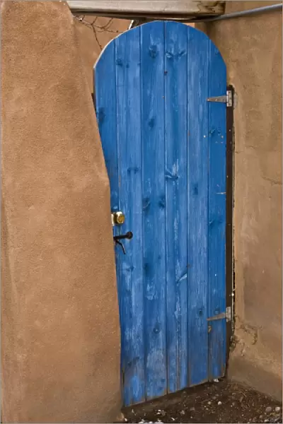 USA, New Mexico, Santa Fe. Blue door contrasts with tan adobe building