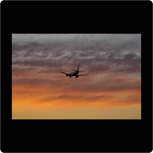 USA, Oregon, Portland. Airplane with landing gear down making a final approach to land at sunset