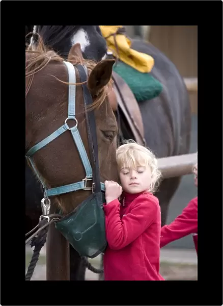 USA. Wyoming. Grand Tetons National Park. Young girl gives affection to a horse in a Tetons stable