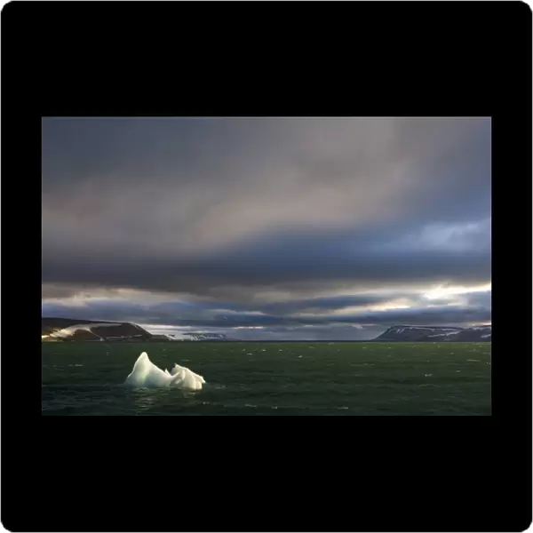 Norway, Svalbard, Nordaustlandet, Setting sun lights iceberg floating in Palanderbukta