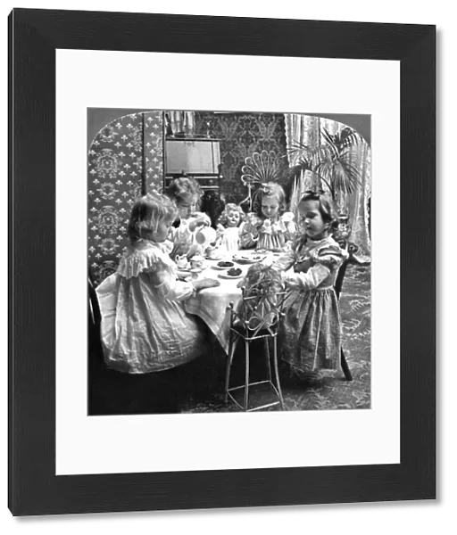 Four girls and their dolls sitting around a table and having a tea party. Stereograph, c1902