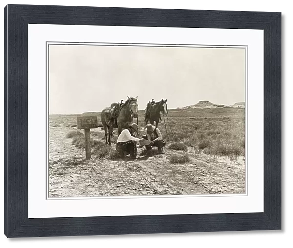 TEXAS: COWBOYS, c1907. Two cowboys reading mail next to a USM postbox near the