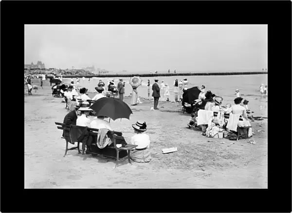 CONEY ISLAND: BEACH, c1910. People seated on park benches by the seashore at Coney Island