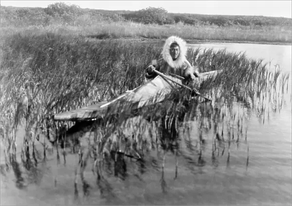 ALASKA: ESKIMO, c1929. An Eskimo muskrat hunter paddling through the marsh, Kotzebue, Alaska
