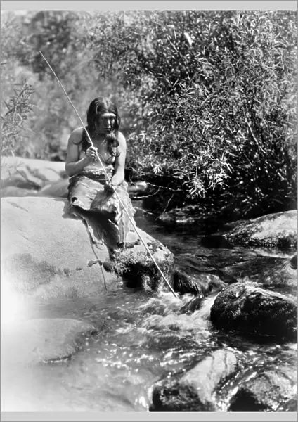 CALIFORNIA: MIWOK MAN, c1924. A Miwok man holding a fishing spear, seated on a