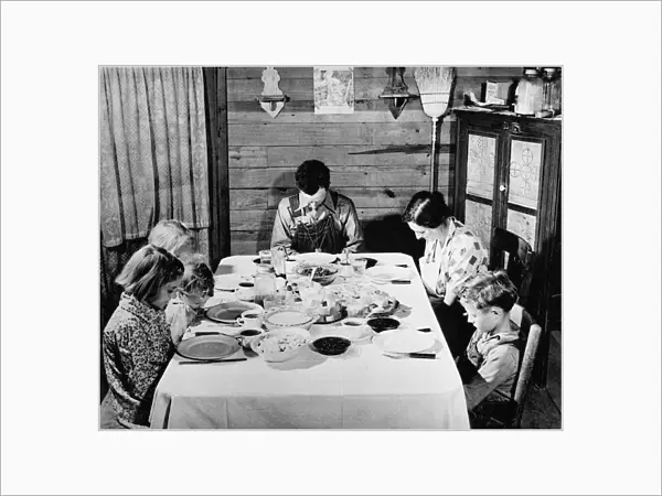 FAMILY SUPPER, 1941. A family saying grace before afternoon supper at home in Carroll County