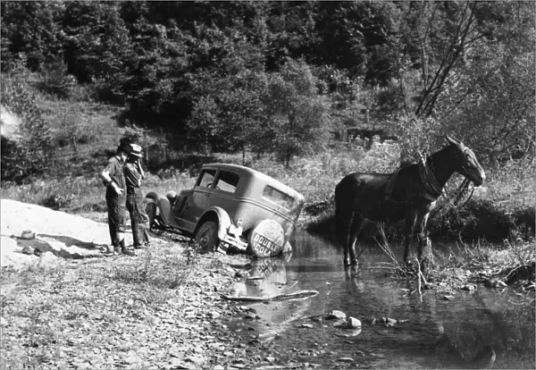 RURAL TRANSPORTATION, 1940. A car stuck in a creek bed after an attempted crossing
