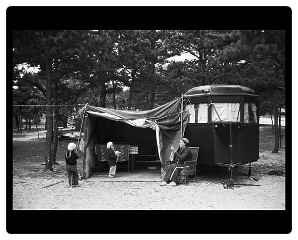 TRAILER CAMP, 1936. A mother and two children in front of their camper at a trailer