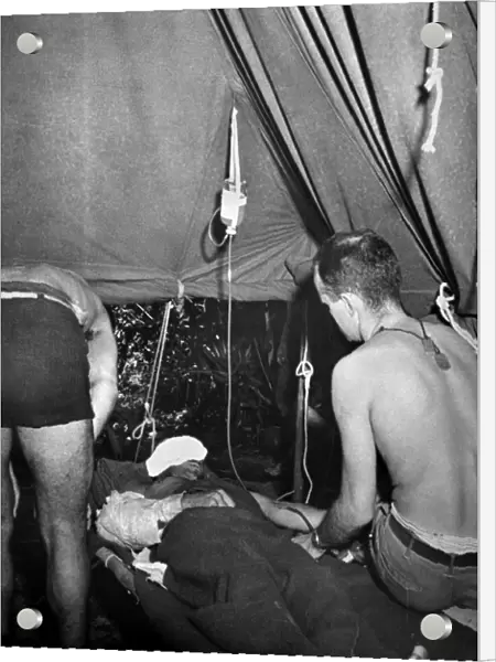 WORLD WAR II: NEW GUINEA. A U. S. Army Lieutenant administers a blood transfusion