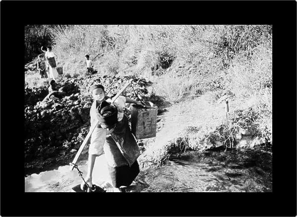 CHINA: SPRING WATER, c1940. A mother collects buckets of drinking water at a spring
