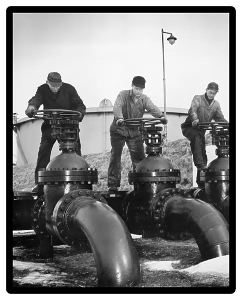 Workers at an Atlantic coast seaport in the United States regulate the flow of oil onto tankers bound for armed forces during World War II. Photographed c1944