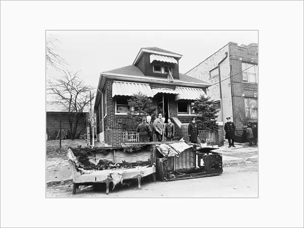 MALCOLM X: HOME, 1965. The charred remains of furniture in front of the home of