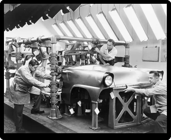 FORD ASSEMBLY LINE, 1954. Three men at work on an automobile on a Ford assembly line