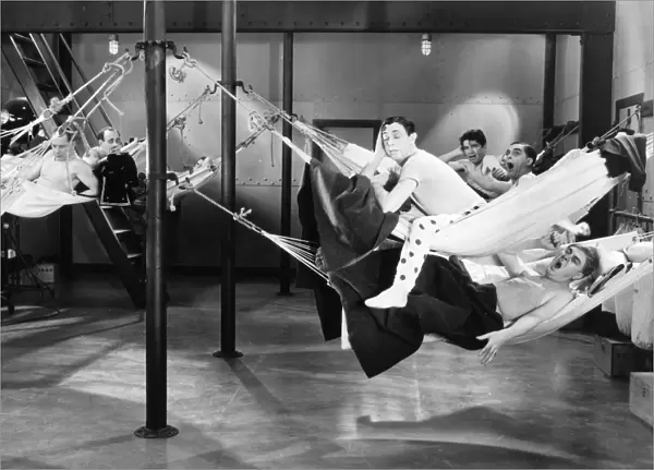 FILM STILL: HAMMOCK, 1920s. Actors in hammocks on a Hollywood film set, suggesting very spacious quarters onboard a navy vessel, 1920s