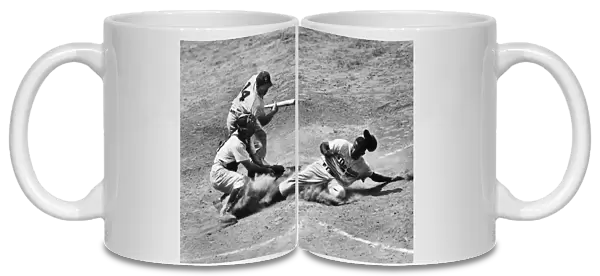 JACKIE ROBINSON (1919-1972). John Roosevelt Robinson, known as Jackie. American baseball player. As a member of the Brooklyn Dodgers, stealing home under the tag of catcher Andy Seminick in a game against the Philadelphia Phillies, at Shibe Park, Philadelphia, Pennsylvania, 2 July 1950. The Dodgers batter is Gil Hodges