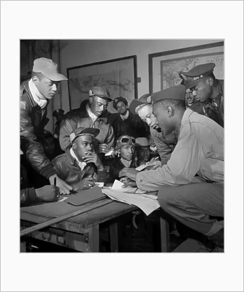 TUSKEGEE AIRMEN, 1945. Members of the Tuskegee Airmen in a meeting at Ramitelli, Italy. Front row seated, left to right: unidentified; Jimmie Wheeler (with goggles); Emile Clifton (cloth cap). Standing, left to right: Ronald Reeves; Hiram Mann; Joseph Chineworth; Elwood Driver; Edward Thomas; Woodrow Crockett. Photograph by Toni Frissell, March 1945