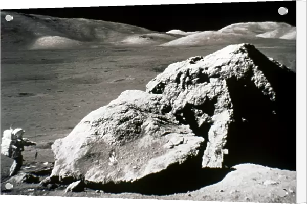 APOLLO 17: BOULDER, 1972. Astronaut Harrison H. Jack Schmitt standing by a huge split boulder on the surface of the moon during the Apollo 17 mission, 13 December 1972