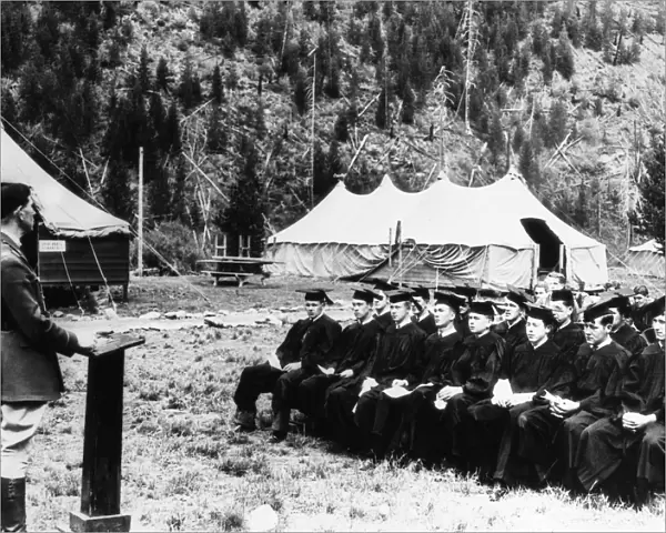 A group of Civilian Conservation Corps workers wearing caps and gowns and listening to Captain Jay Gleason give a speech after receiving their high school diplomas, at a camp at Clark Fork, Idaho, September 1936