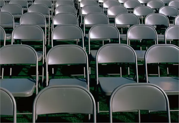 These are empty, grey folding chairs awaiting the crowd to attend the U. S. Naval Academy, Graduation Ceremony. They are neatly set up in rows side by side
