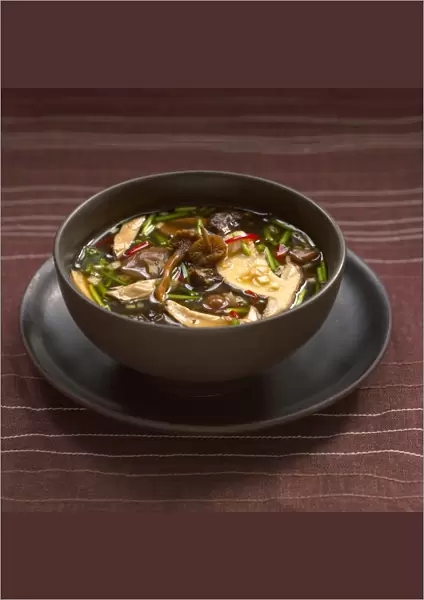 Bowl of wild mushroom and miso broth, on a plate