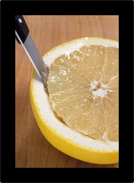 Segmenting a grapefruit, cutting out the flesh with a serrated knife