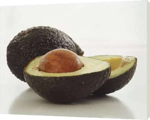 Halved and whole avocado, close up
